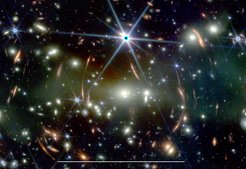 This JWST image shows the galaxy cluster SMACS J0723.3−7327 with a large number of lensed background galaxies. The white bar at the bottom corresponds to 50 arcsec, which is approximately the maximum size of Jupiter observed from Earth.