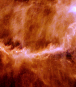 Die bekannte Sternentstehungsregion in der Molekularen Wolke im Sternbild Stier enthält das Filament B211, hier beobachtet mit dem Herschel-Satellitenteleskop. Ober- und unterhalb des Filaments erkennt man schwach dünne "Schlieren", die dem Magnetfeld der Wolke folgen. Mit Radioteleskopen sieht man, wie Gas entlang dieser Streifen zum Filament strömt, geleitet durch das Magnetfeld. In dem dichten Gas das sich dadurch im Filament ansammelt bilden sich Sterne; einige sind bereits als helle Punkte sichtbar.